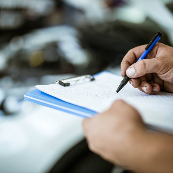 A close up of hand checking things off alist on an indescript clipboard.
