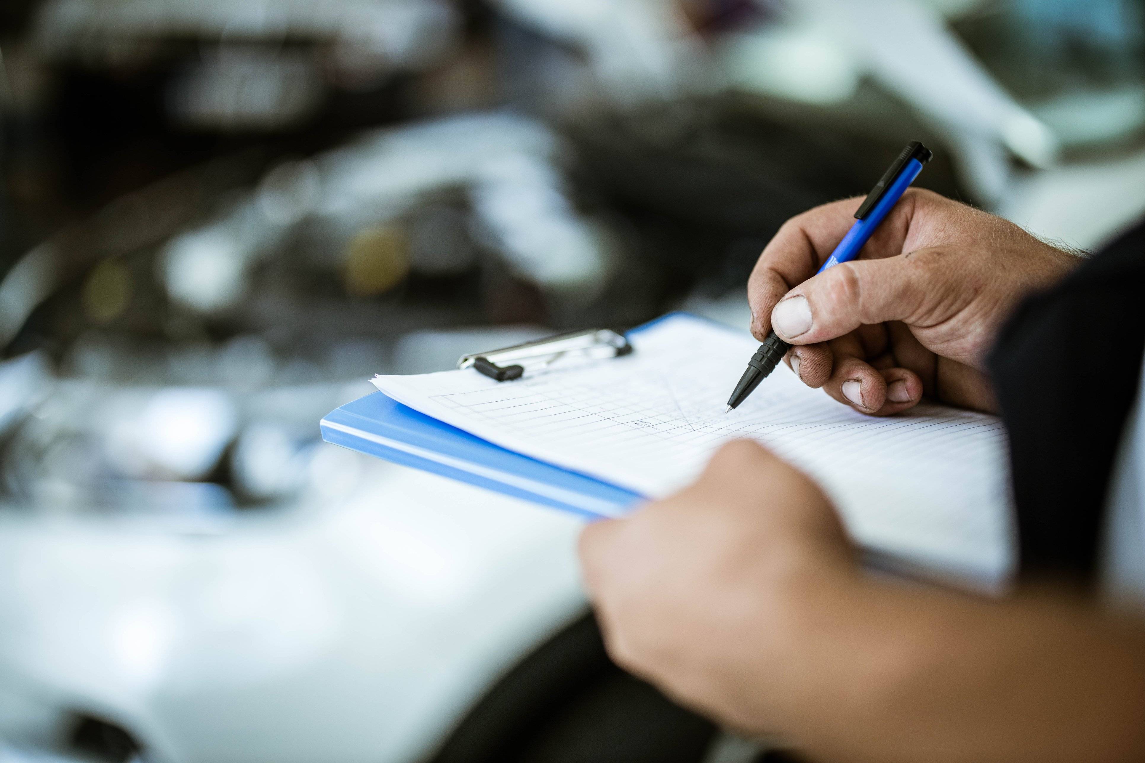 A close up of hand checking things off alist on an indescript clipboard.