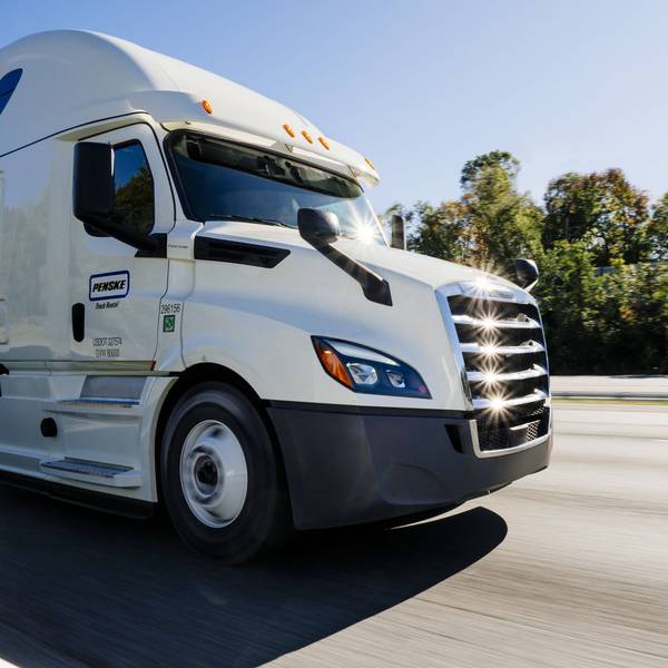 A closeup of a white Penske semi-truck tractor on the road.