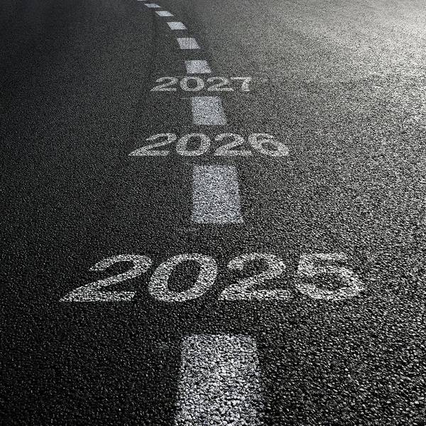A closeup of as asphalt road with the years 2025, 2026, and 2027 painted on it.