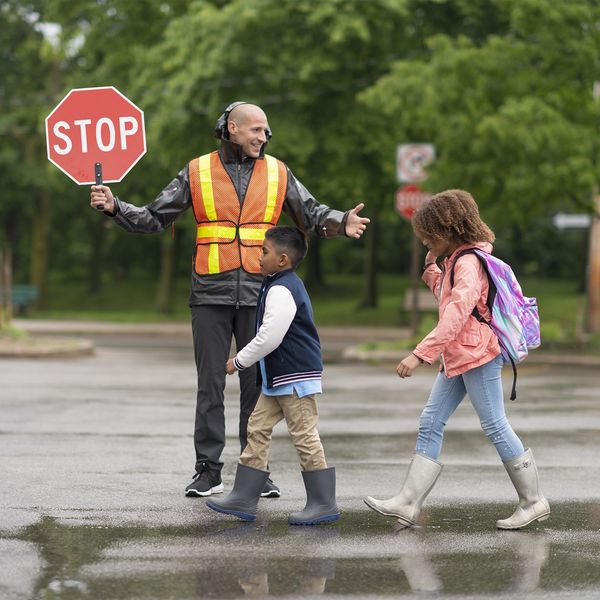 A crossing guard stops traffic as children cross the street to school.