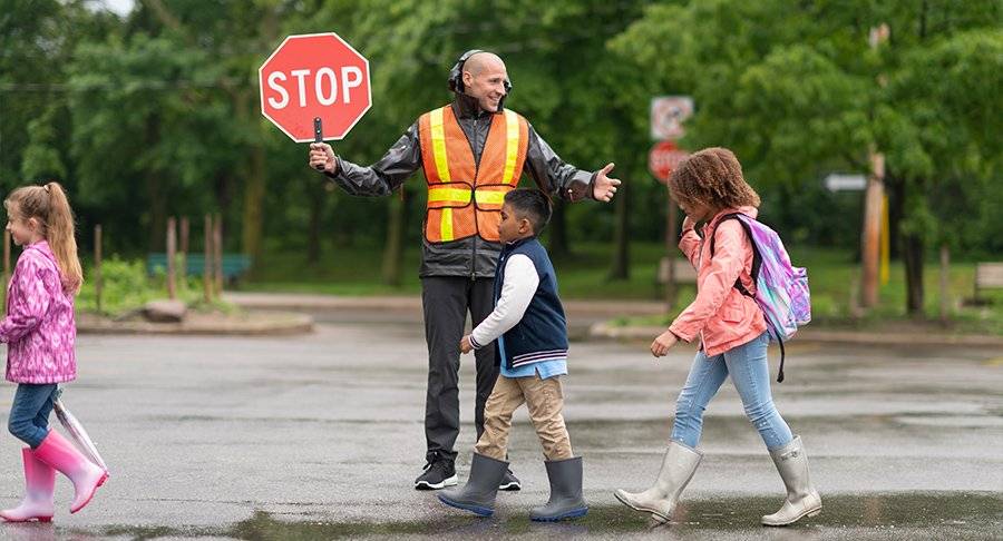 A crossing guard stops traffic as children cross the street to school.