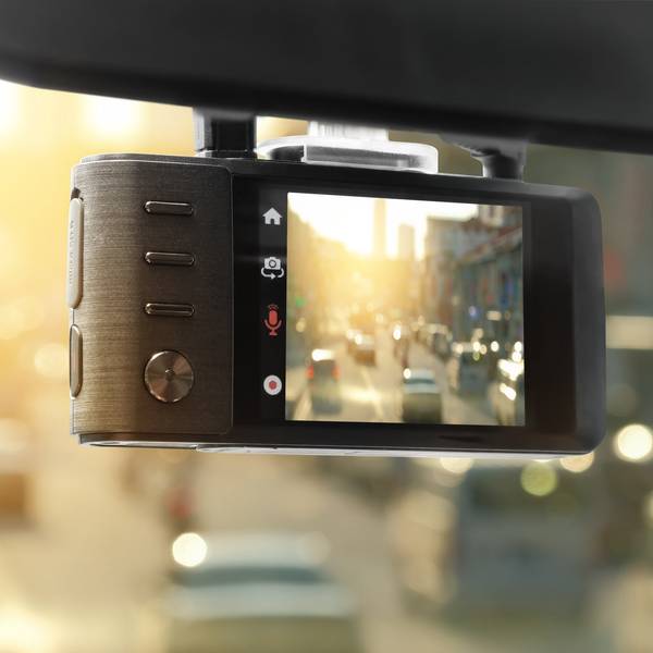 A dash cam hanging from the windshield pointing out at busy traffic.