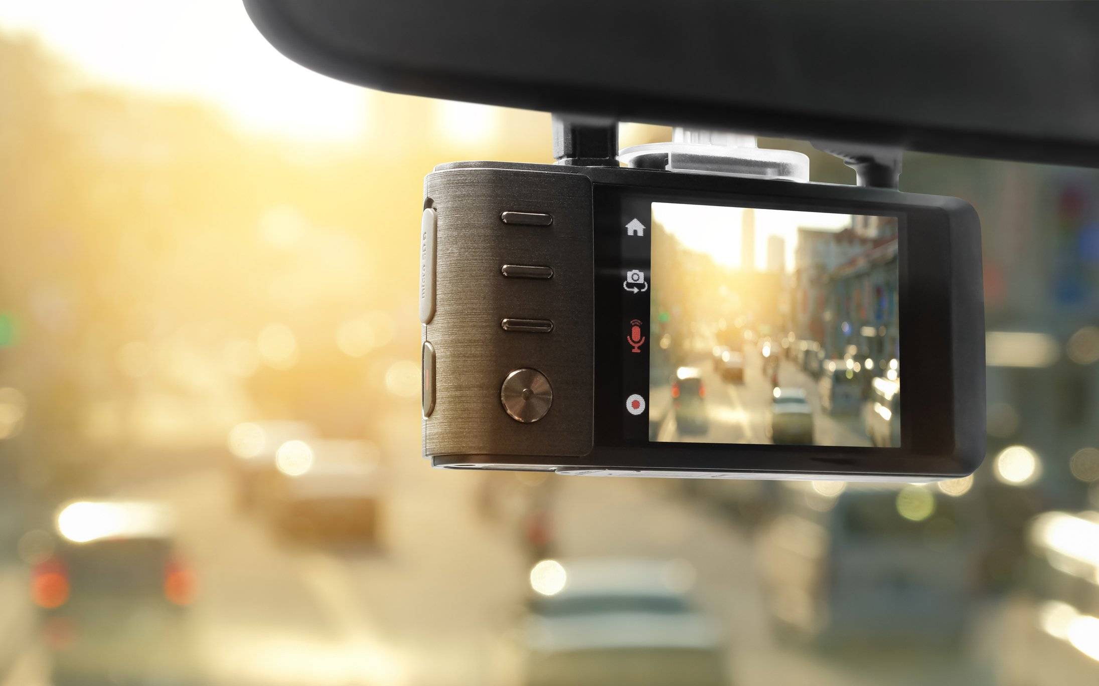 A dash cam hanging from the windshield pointing out at busy traffic.