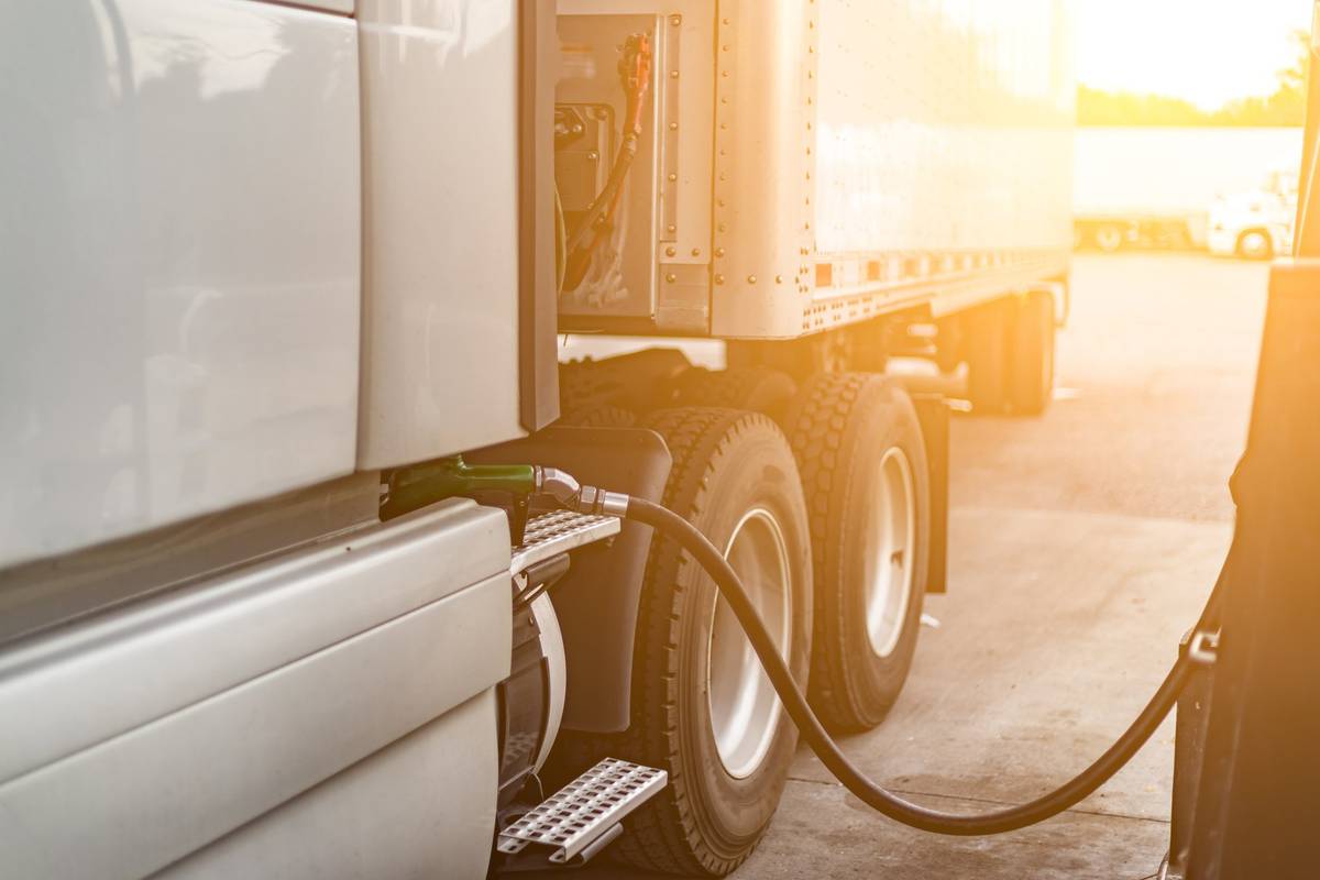 A diesel pump stuck into the fuel tank of a white semi-truck.