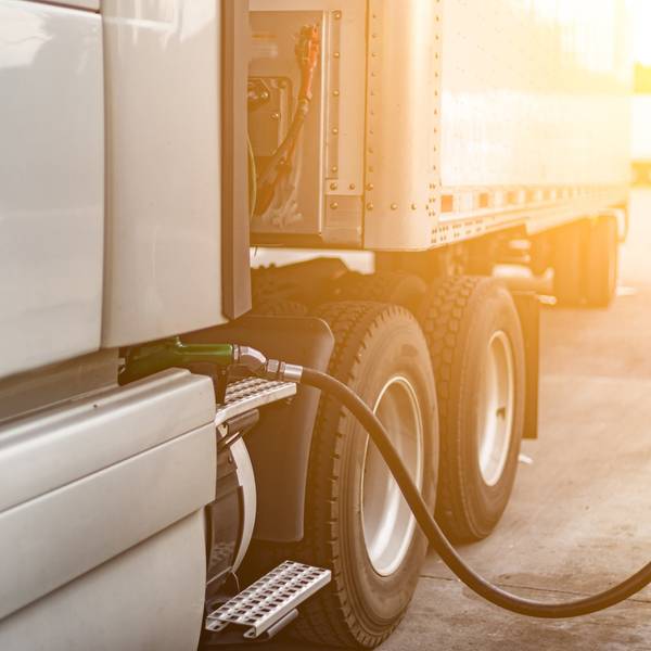 A diesel pump stuck into the fuel tank of a white semi-truck.