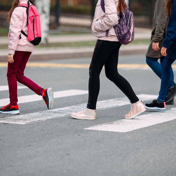 A group of kids with backpacks cross the street on the way to school.