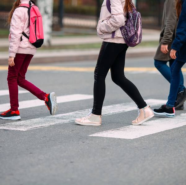 A group of kids with backpacks cross the street on the way to school.