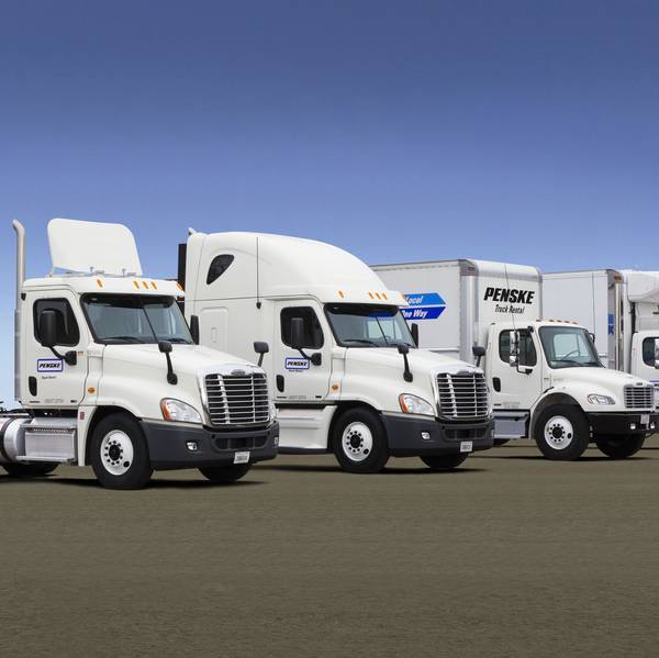 A lineup of four white Penske Leasing trucks.