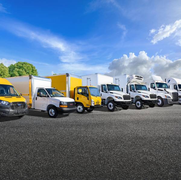 A lineup of yellow and white Penske trucks in a parking lot.