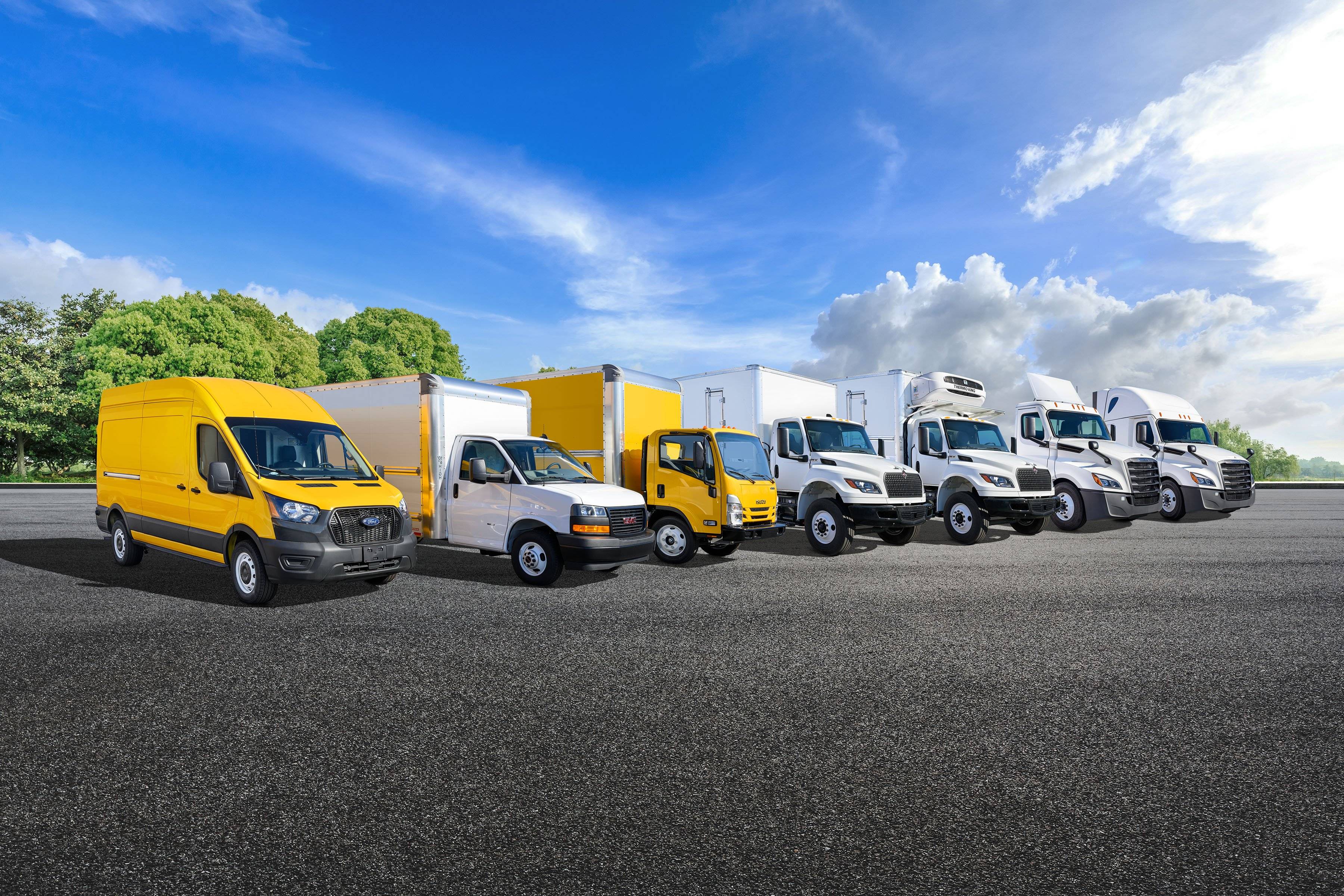 A lineup of yellow and white Penske trucks in a parking lot.