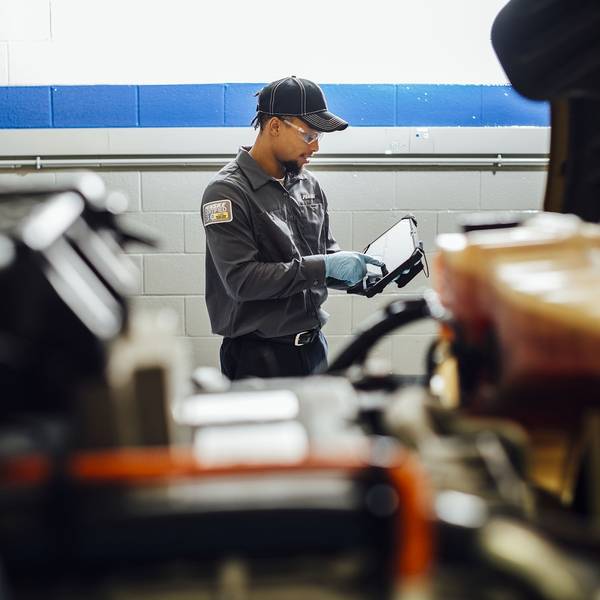A maintenance technician documents something on an ipad.