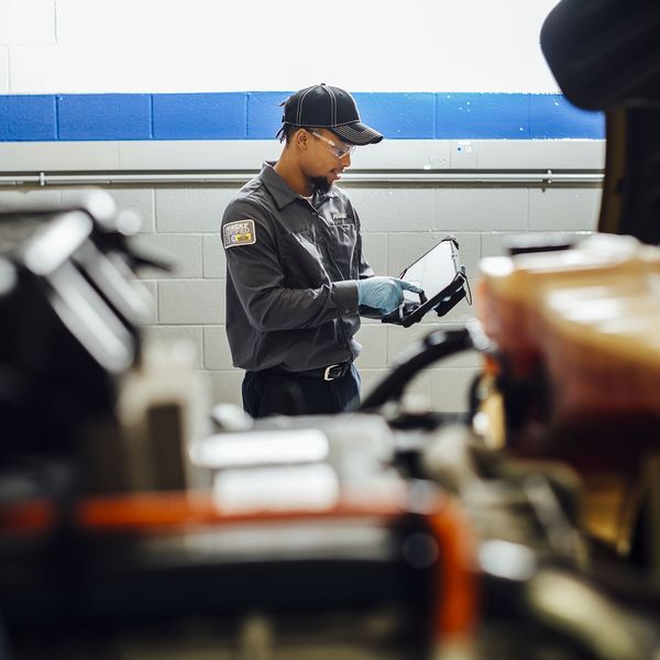 A maintenance technician documents something on an ipad.