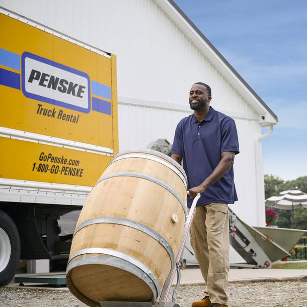 A man pushes a wine barrel off a Penske truck at a vineyard.
