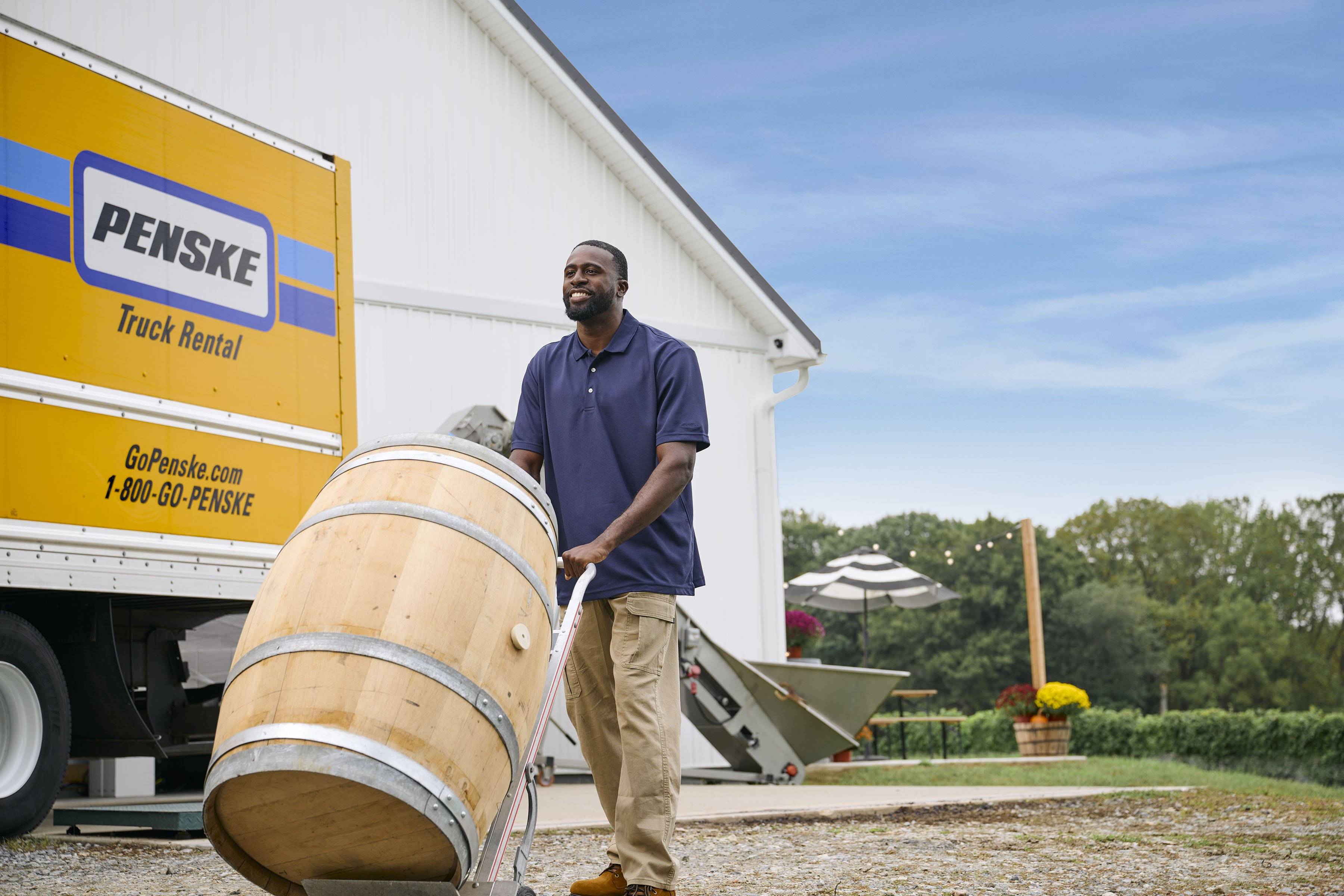 A man pushes a wine barrel off a Penske truck at a vineyard.