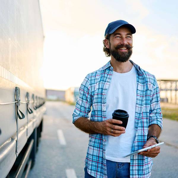 A man walks in a parking lot next to a semi-truck.