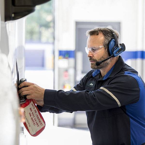A Penske mechanic in blue works on fixing a truck.