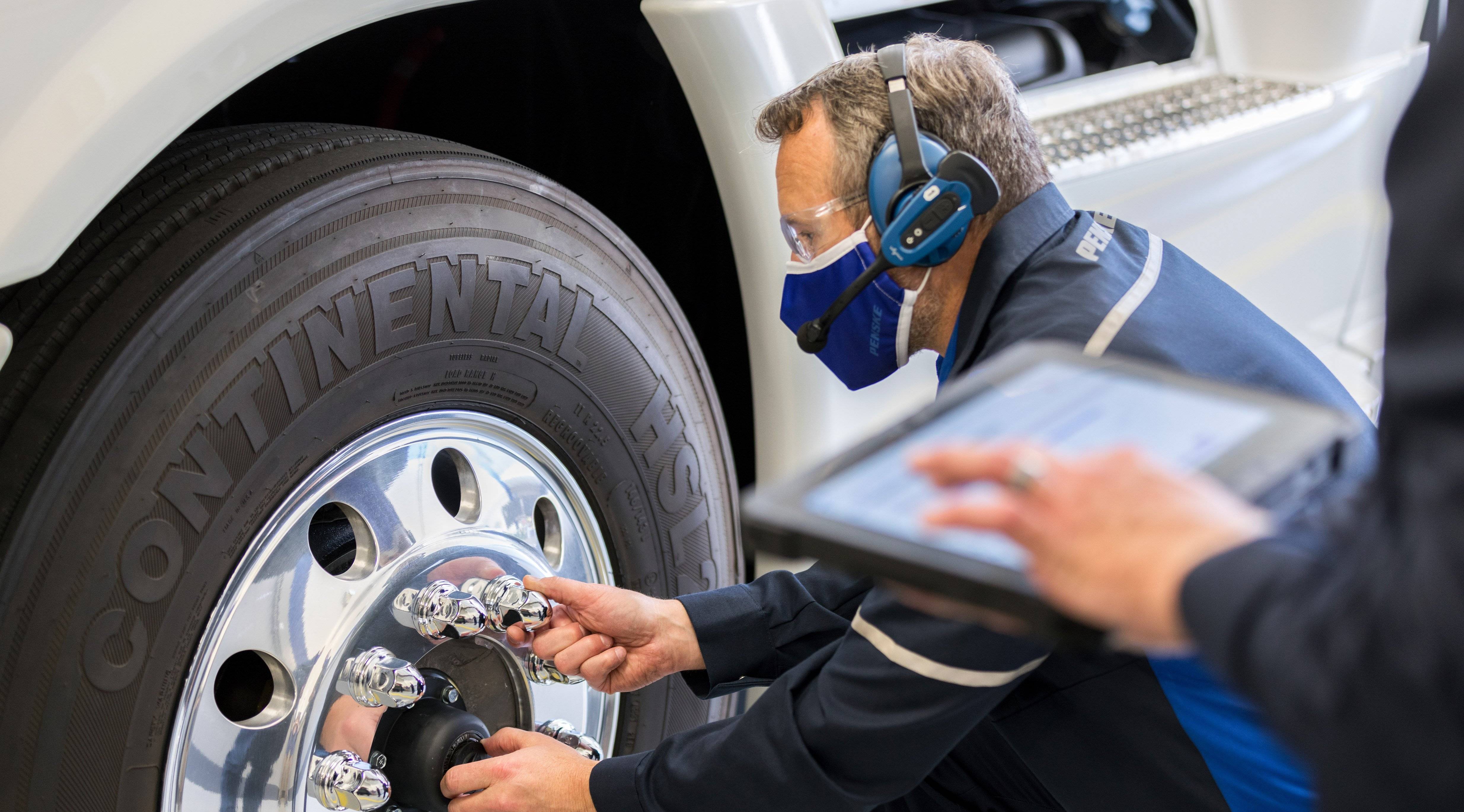 A Penske mechanic works on a truck tire.