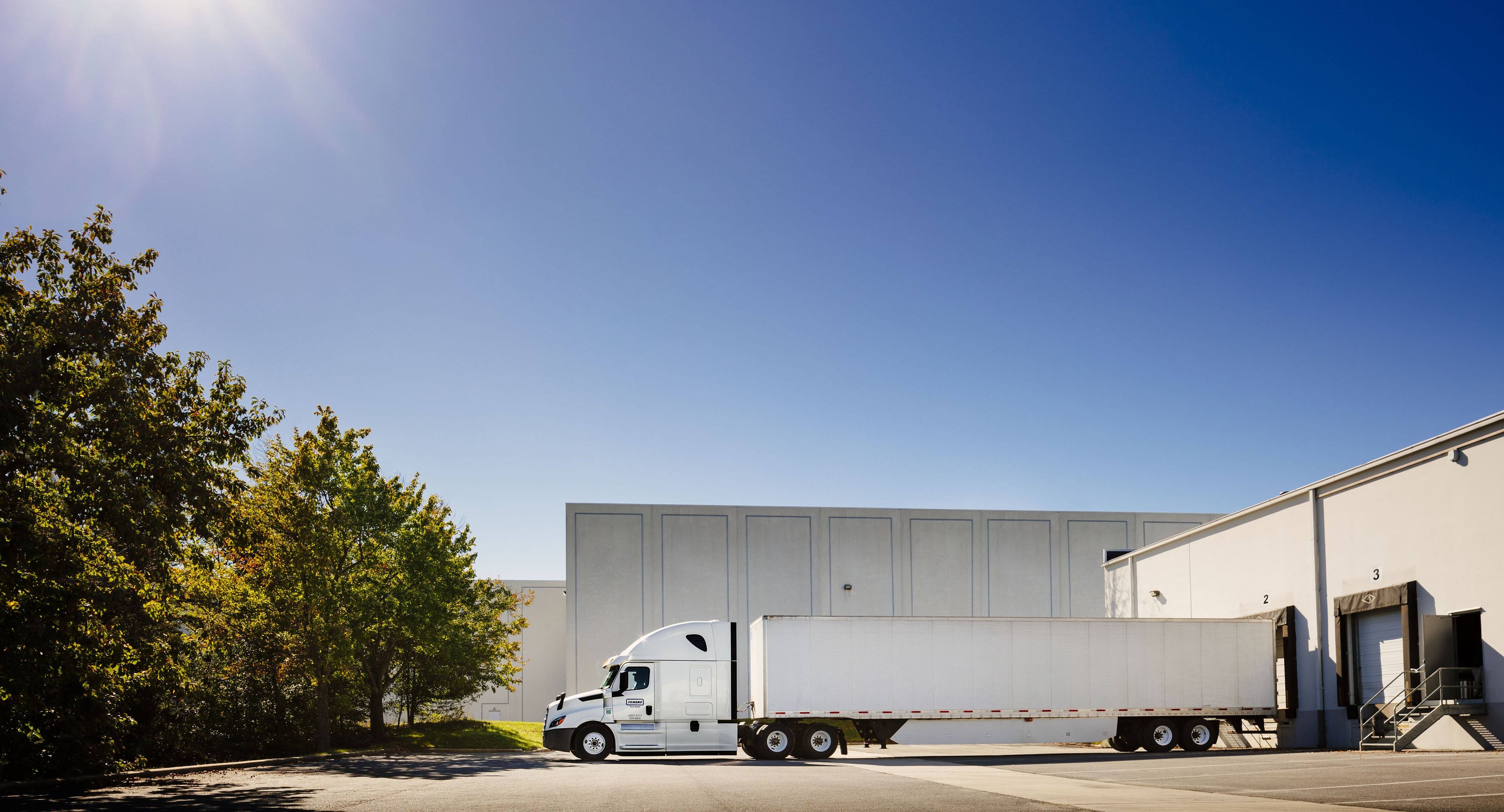 A penske semi-truck and trailer at a loading dock.