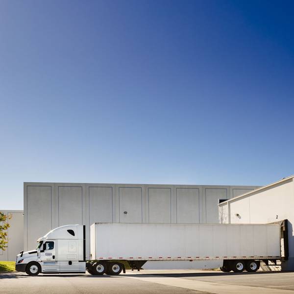 A penske semi-truck and trailer at a loading dock.