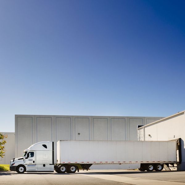 A penske semi-truck and trailer at a loading dock.