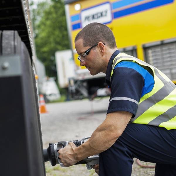 A Penske technician works on the tire of a truck.