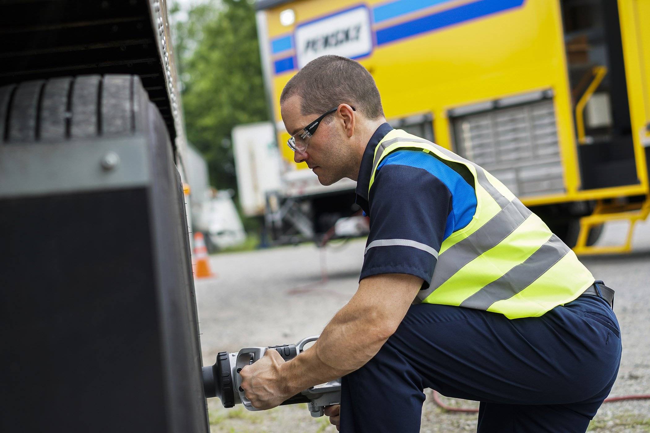 A Penske technician works on the tire of a truck.