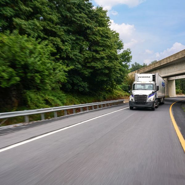 A Penske tractor and refrigerated trailer drive on a road.