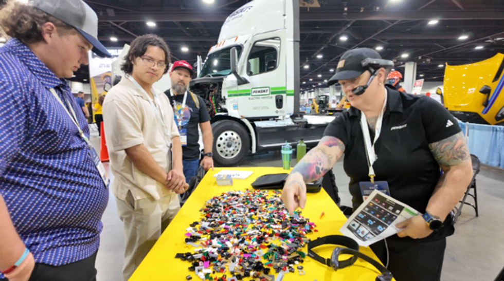 A person behind a table pointing to pieces on a table