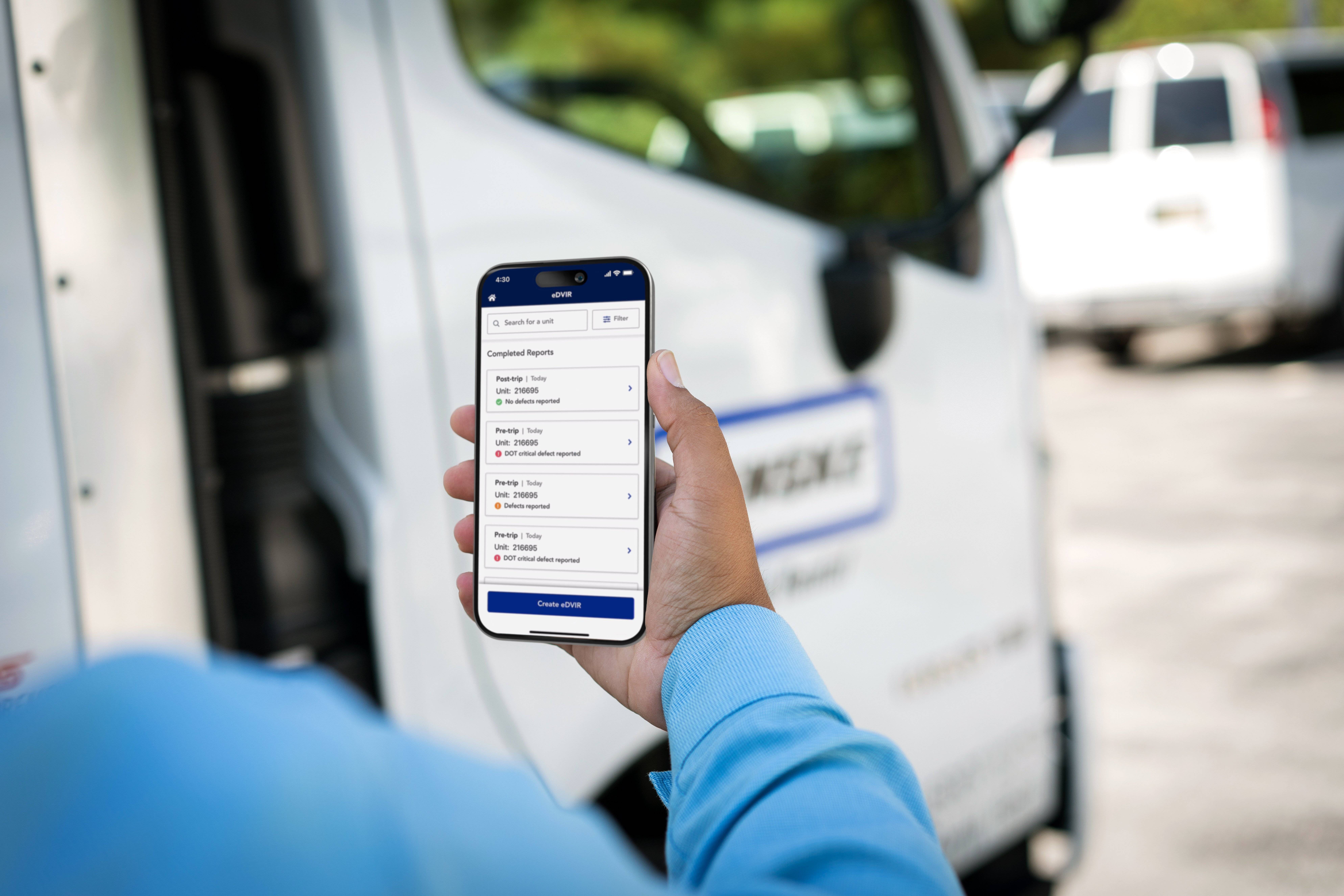 A person holds a smartphone displaying the Penske Driver mobile app's eDVIR feature.