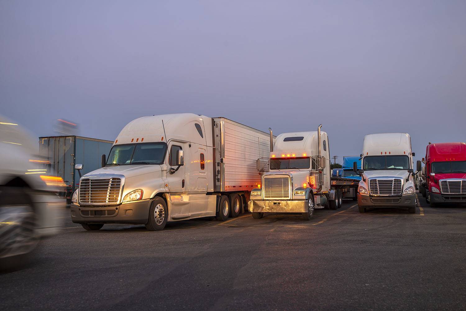 A row of parked semi-trucks with their headlights on.