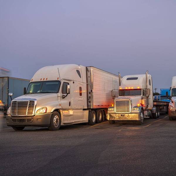 A row of parked semi-trucks with their headlights on.