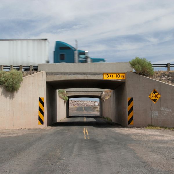 A semi truck drives over a bridge with a clearance of 13 feet, 10 inches.