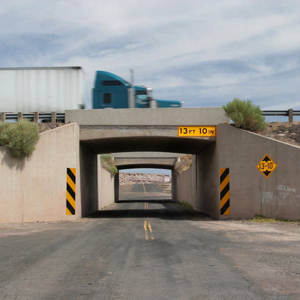 A semi truck drives over a bridge with a clearance of 13 feet, 10 inches.
