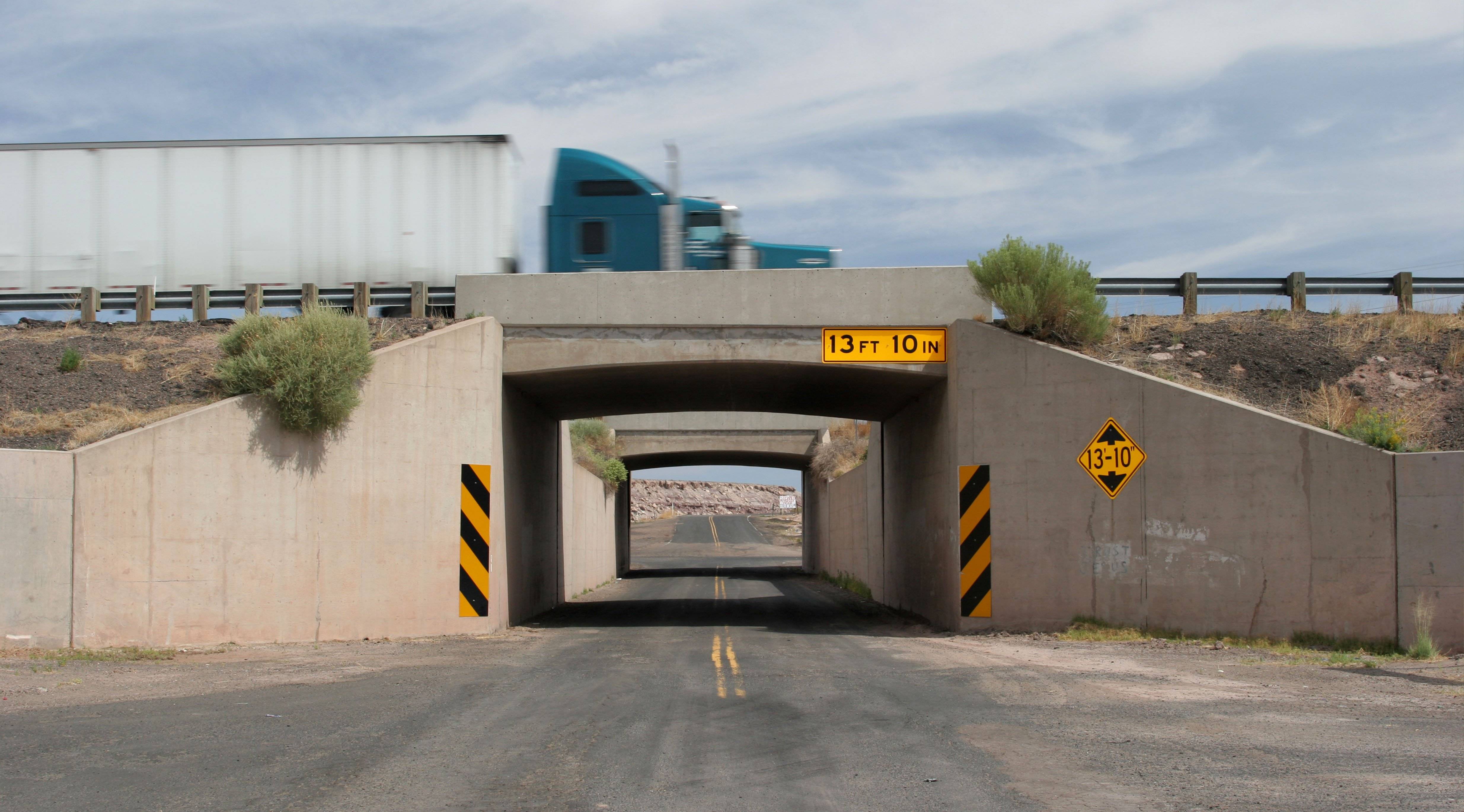 A semi truck drives over a bridge with a clearance of 13 feet, 10 inches.