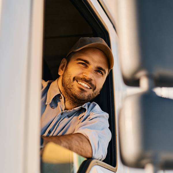 A smiling truck drivers looks out his driver-side truck window.