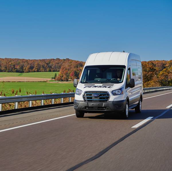 A white Penske cargo van drives up the road.