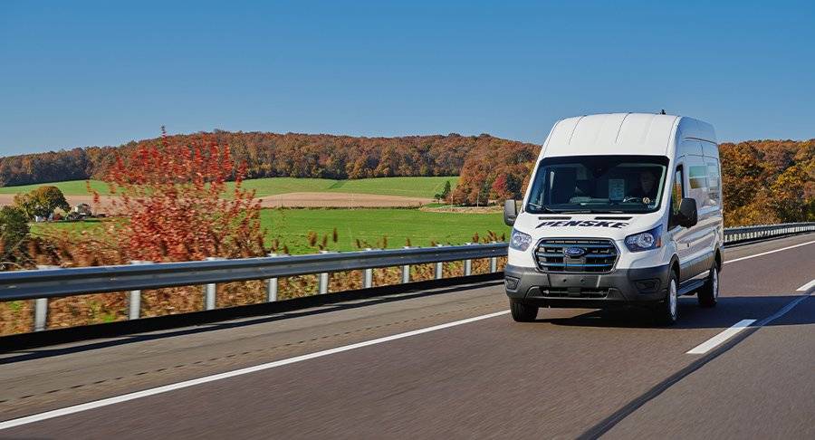 A white Penske cargo van drives up the road.