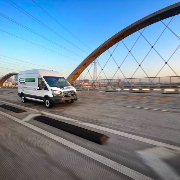 A white Penske electric cargo van drives over a bridge.