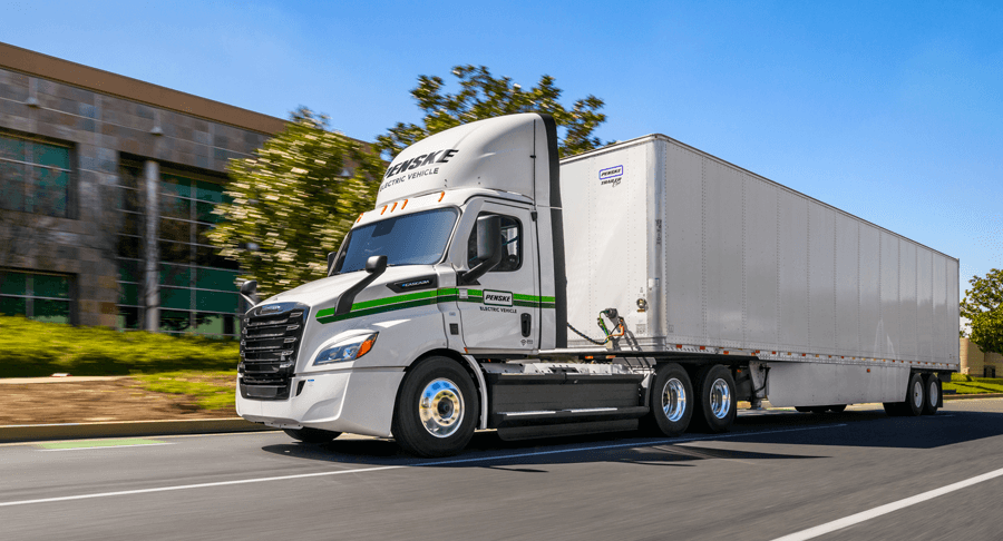 A white Penske semi truck driving down the road