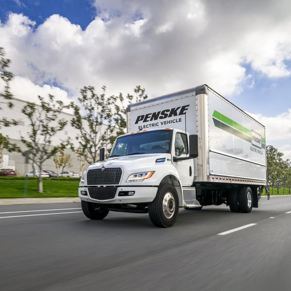A white Penske truck drives on the road.