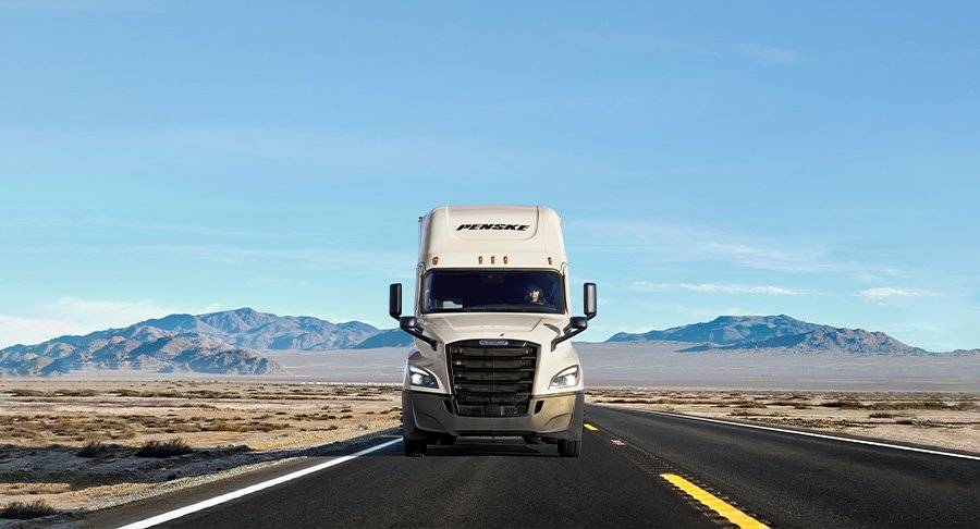 A white Penske truck on the road