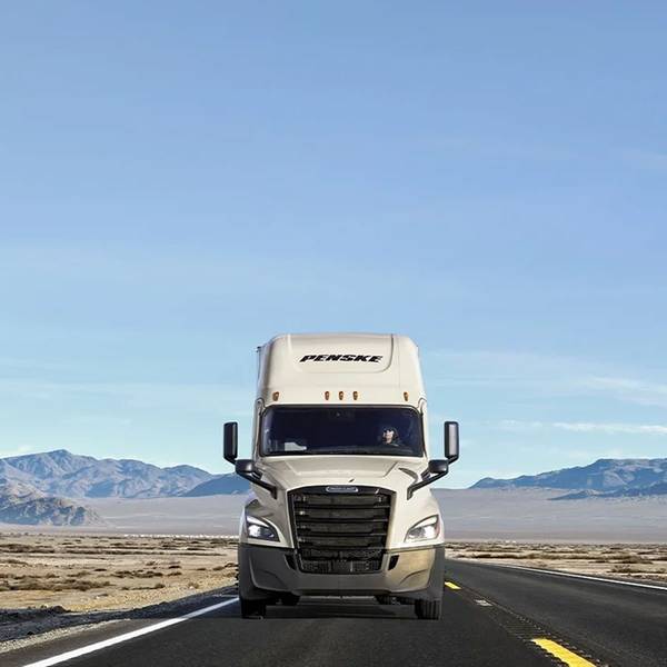 A white Penske truck on the road