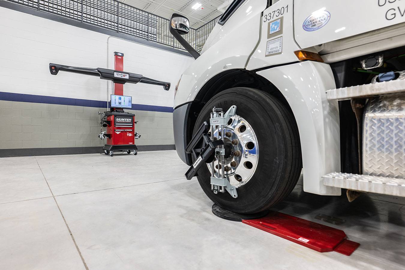 A white semi-truck sits in a collision maintenance bay.