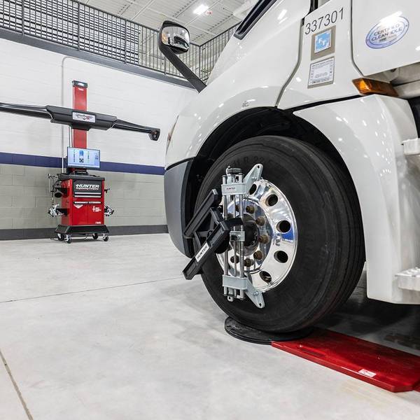 A white semi-truck sits in a collision maintenance bay.