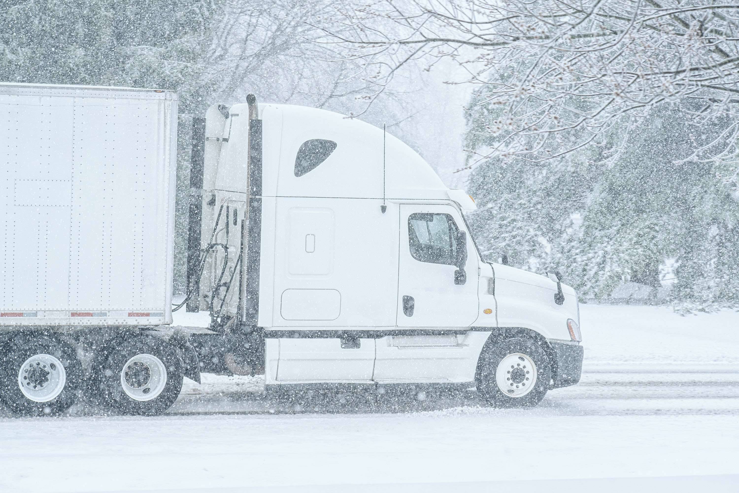 A white semi-truck sits on a snowy street.