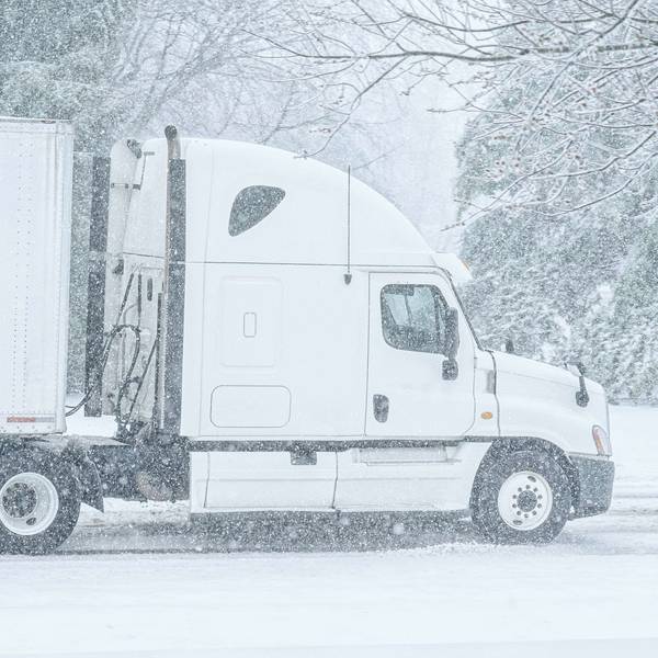 A white semi-truck sits on a snowy street.