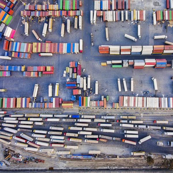 An above view looking down into a very busy shipping yard with containers and trucks lined up.