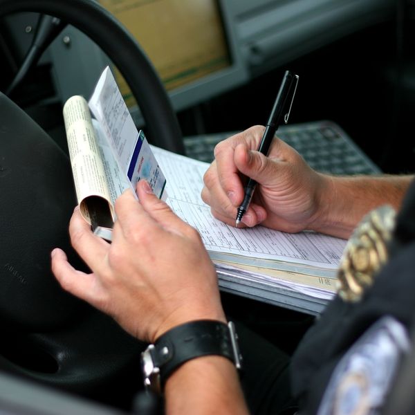 An officer writes out a citation while sitting in his car.