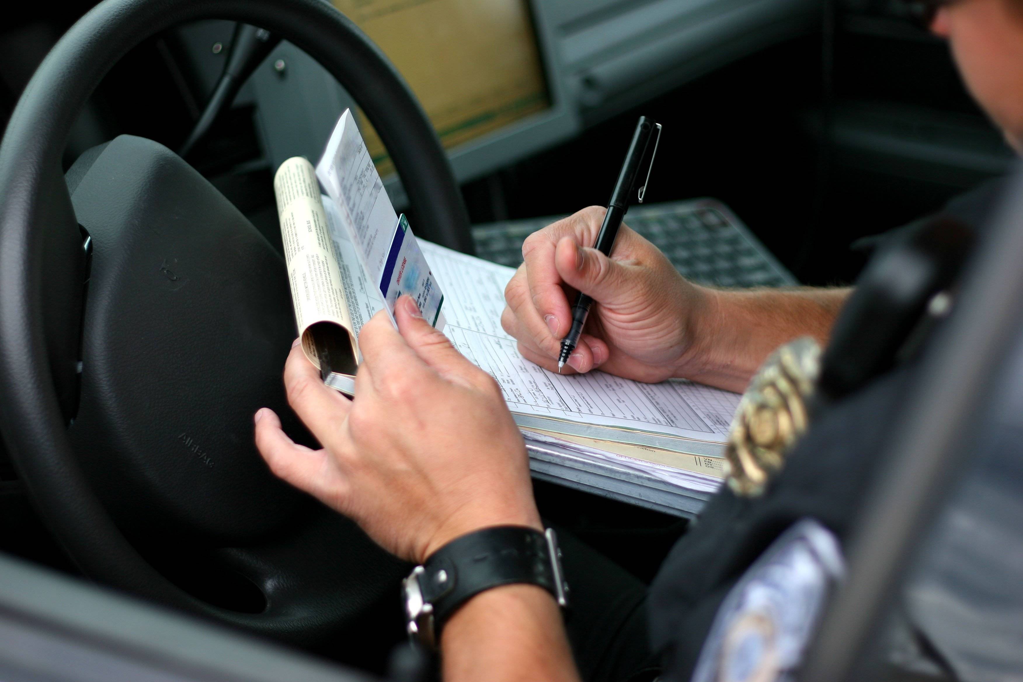 An officer writes out a citation while sitting in his car.